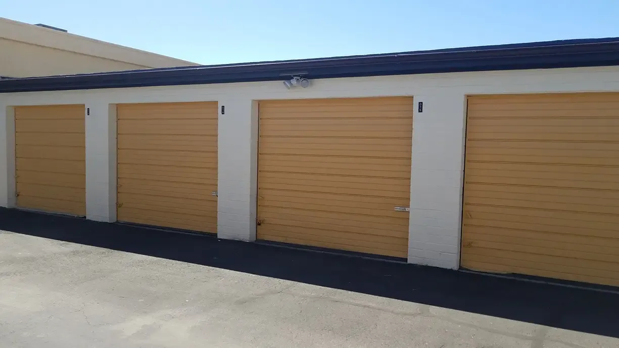 drive up storage units with yellow doors and flood lights near the center of the structure
