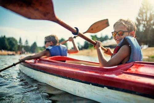 Children Smiling and Paddling in a Kayak