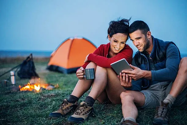 Couple Camping Outside with Fire, Coffee, Tent, and iPad