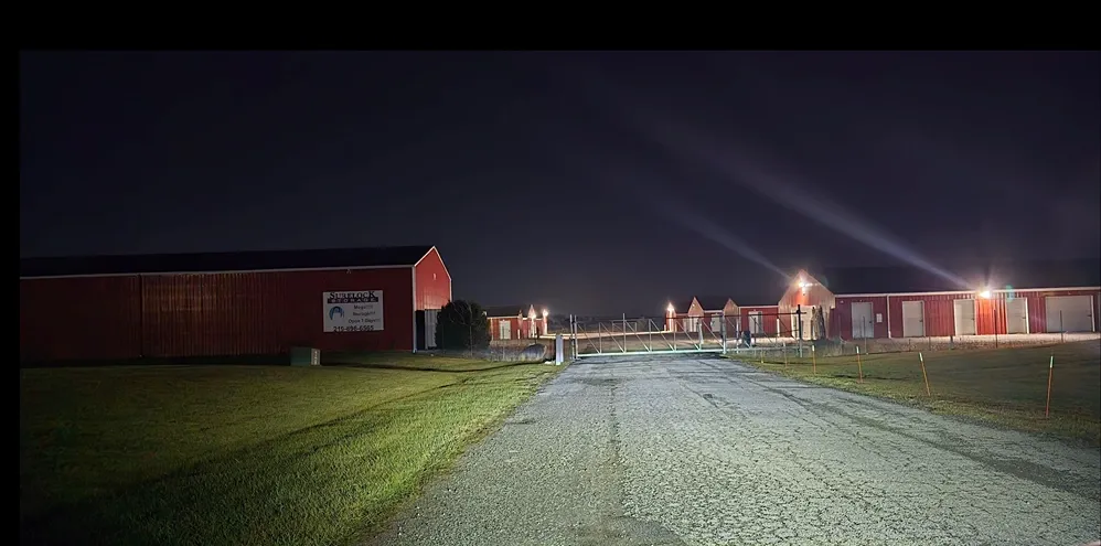 Well lit outdoor storage units with gravel road.