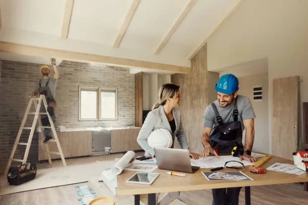 Couple Smiling while Reviewing Home Renovation Plans On Site