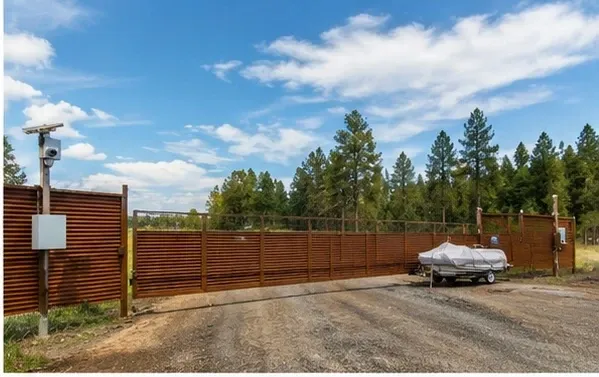 Gravel driveway with metal fencing and an entrance gate