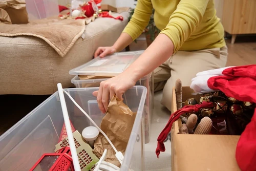 A woman packing belongings into a clear storage container.