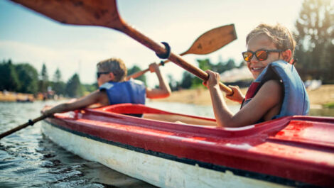 Children Smiling and Paddling in a Kayak