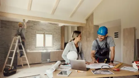 Couple Smiling while Reviewing Home Renovation Plans On Site